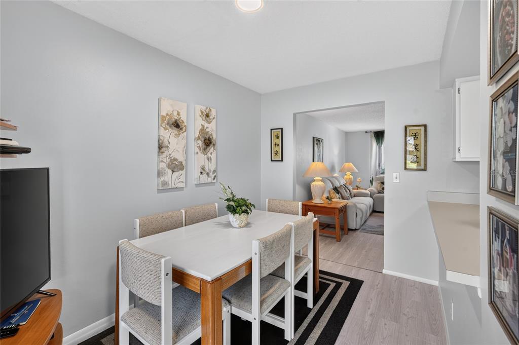 A dining area with a white table and chairs sits adjacent to a living room — 1453 CASA PARK CIRCLE, WINTER SPRINGS, FL