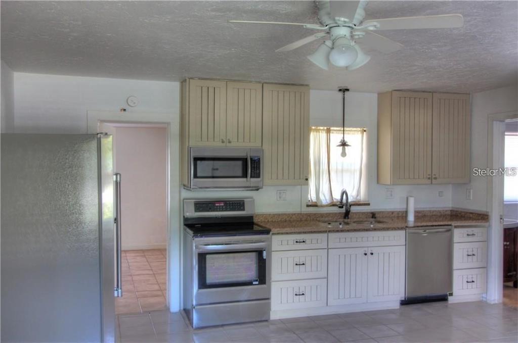 A kitchen features stainless steel appliances, light-colored cabinetry, and a ceiling fan — 613 SHORE ROAD, NOKOMIS, FL