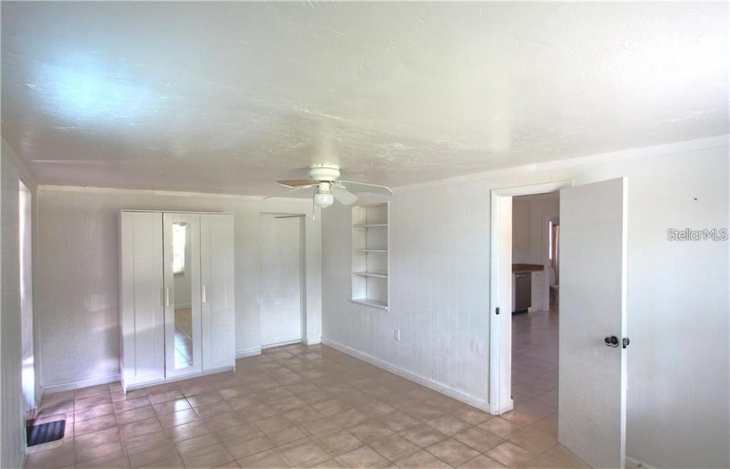 A room with white walls, tiled floors, a ceiling fan, and built-in wall shelving — 613 SHORE ROAD, NOKOMIS, FL