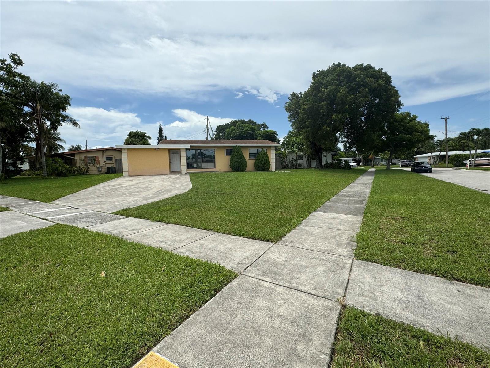 A single-story yellow house with a concrete driveway and sidewalk sits on a grassy lot — 6101 NW 18th Street, Margate FL 33063, MARGATE, FL