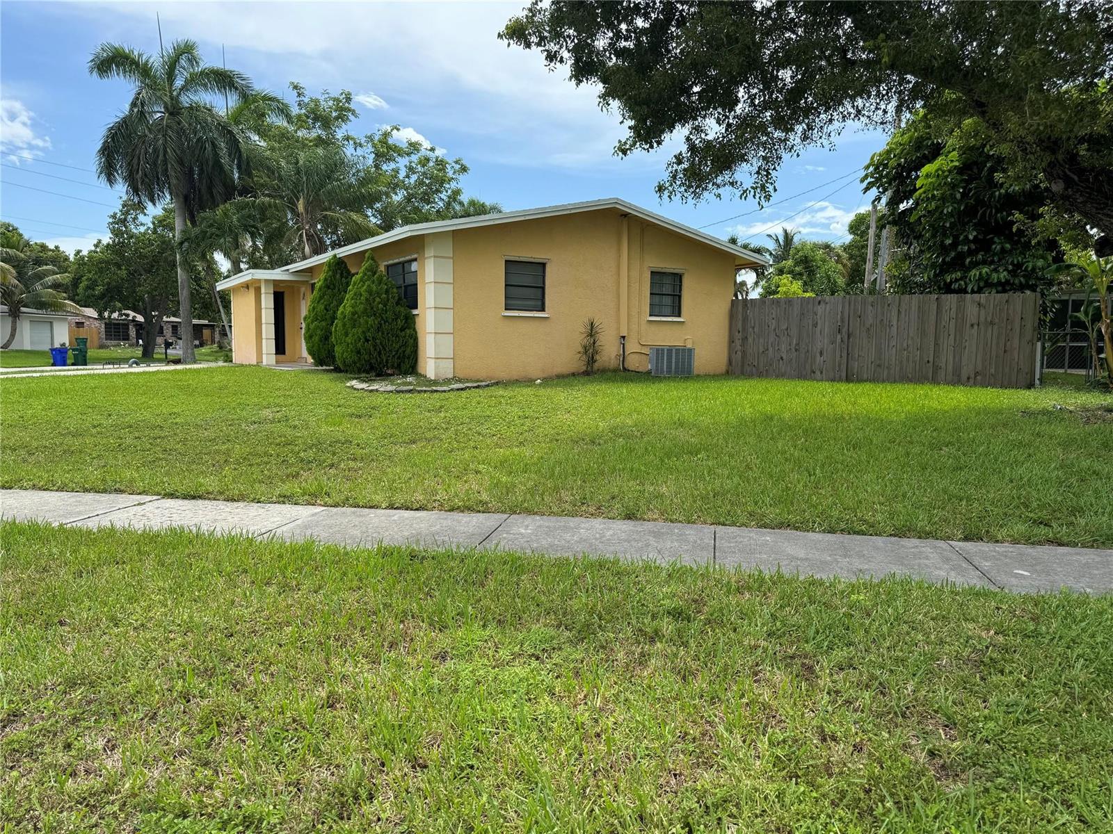 A yellow single-story house with a wooden fence and palm trees on a grassy lot — 6101 NW 18th Street, Margate FL 33063, MARGATE, FL