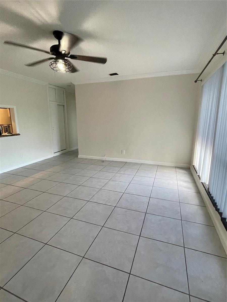 An empty room features light-colored tile flooring, a ceiling fan, and vertical window blinds — 6101 NW 18th Street, Margate FL 33063, MARGATE, FL