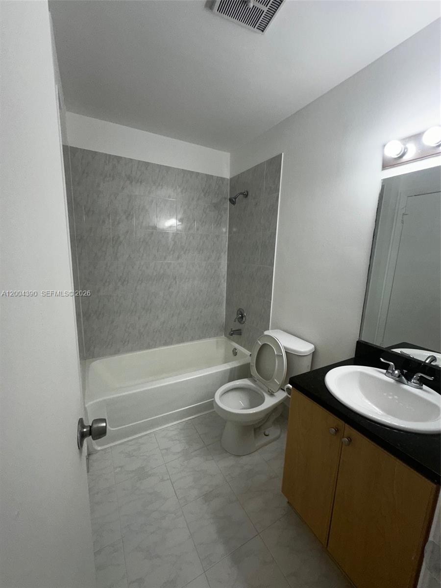 A bathroom features a white tub with gray tile walls, a toilet, and a vanity — 7220 NW 179th St # 201, Hialeah FL 33015, HIALEAH, FL