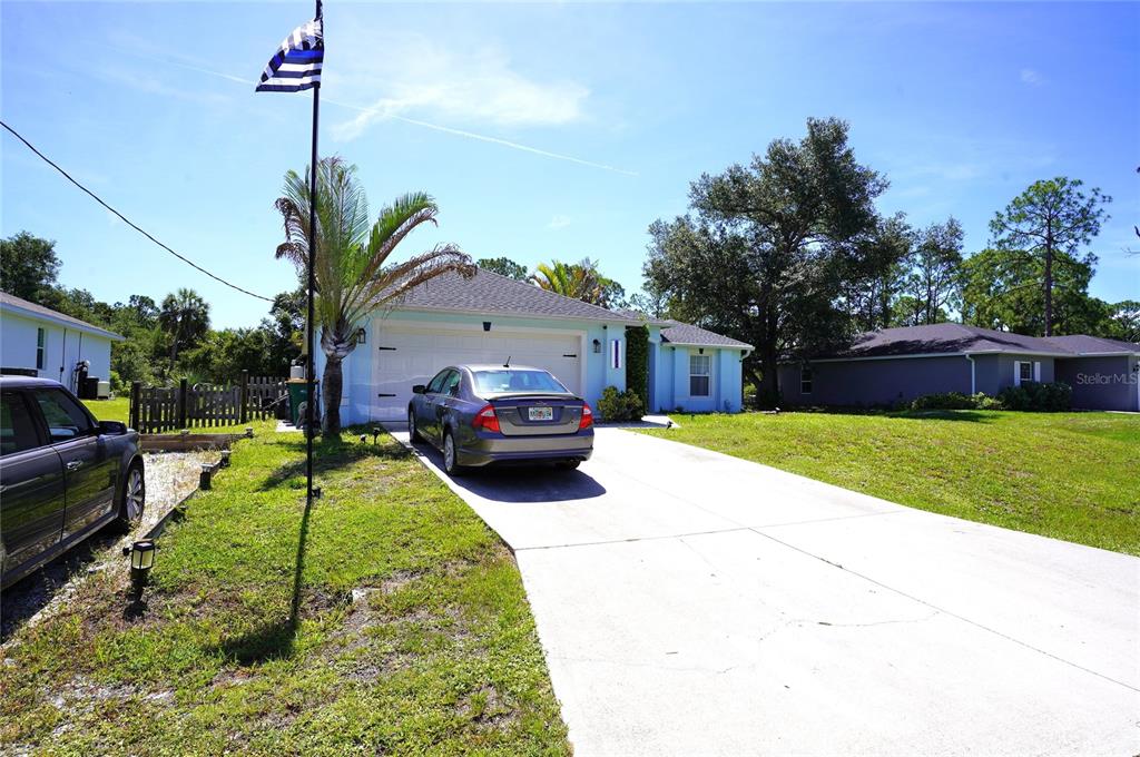 A light blue house with a two-car garage and a concrete driveway under blue skies — 2376 DODGE STREET, PORT CHARLOTTE, FL