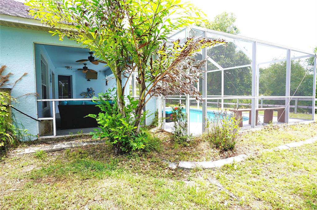 A screened-in patio with a ceiling fan overlooks a swimming pool in a fenced backyard — 2376 DODGE STREET, PORT CHARLOTTE, FL