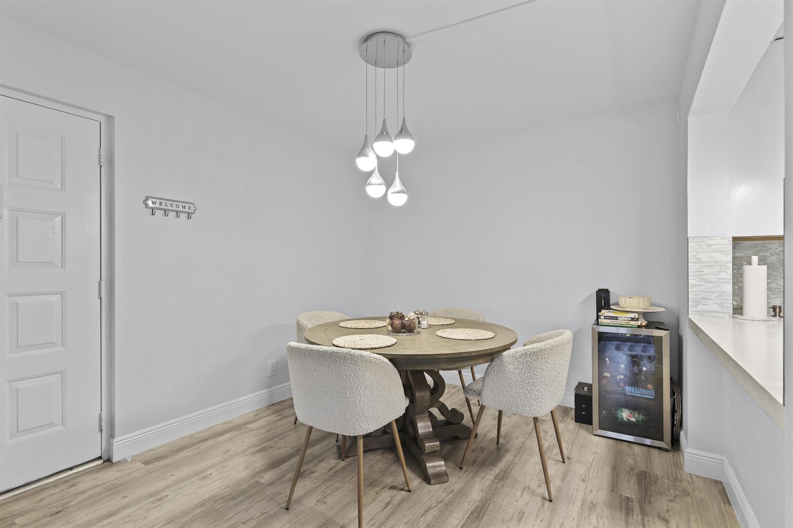 A dining area features a round wooden table, four textured chairs, and a modern pendant light — 629 Sea Pine Way # D2, FL 33415, FL