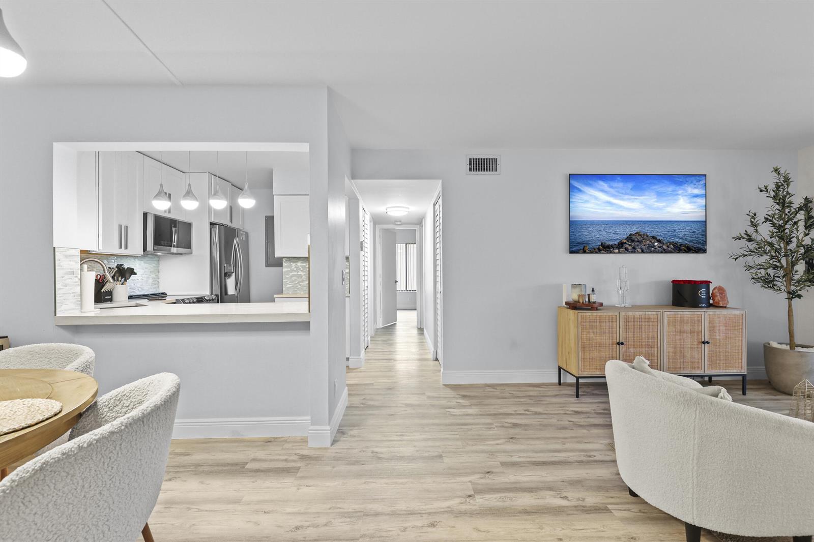A bright living area features light wood flooring, a kitchen pass-through, and a hallway — 629 Sea Pine Way # D2, FL 33415, FL