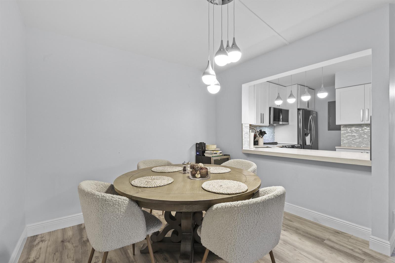 A dining area with a round wooden table and four chairs sits beside a kitchen pass-through — 629 Sea Pine Way # D2, FL 33415, FL