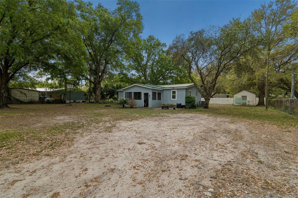 A light blue single-story house sits on a large, sandy lot with mature trees — 4505 ESTATE DRIVE, PLANT CITY, FL