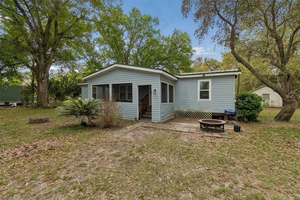 A light blue house with a screened porch and a small stone patio in the yard — 4505 ESTATE DRIVE, PLANT CITY, FL