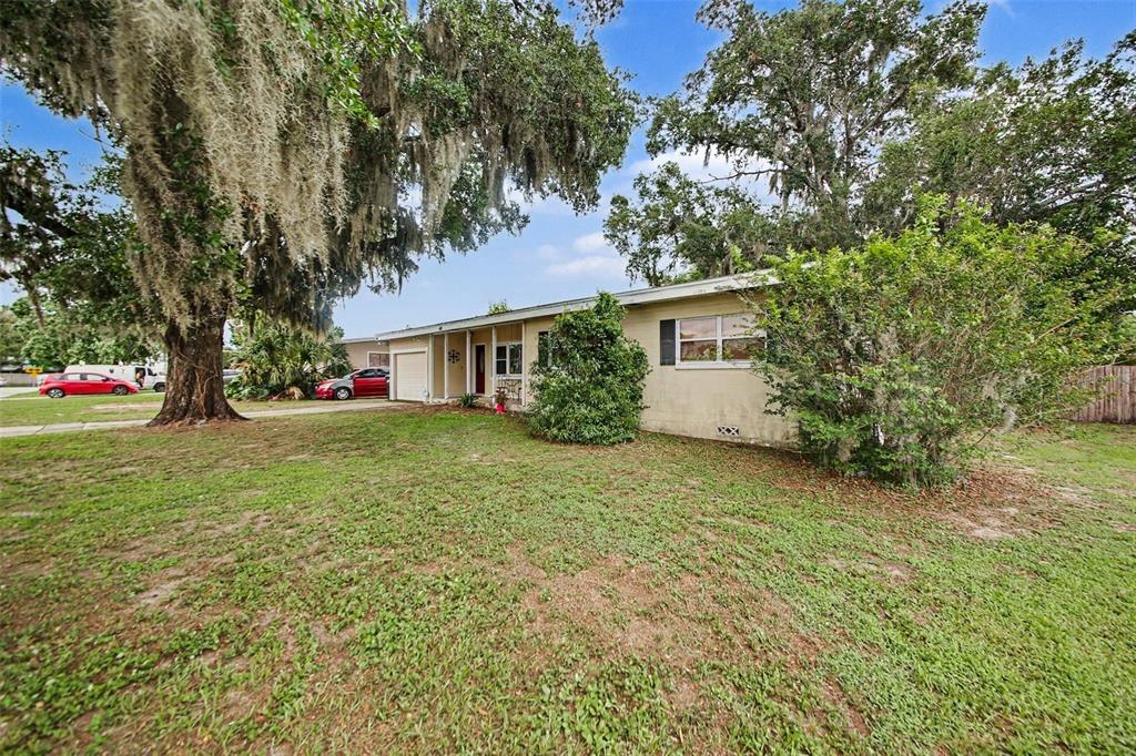 A single-story house with a beige exterior, a front lawn, and large moss-draped oak trees — 1909 JASPER DRIVE, ORLANDO, FL