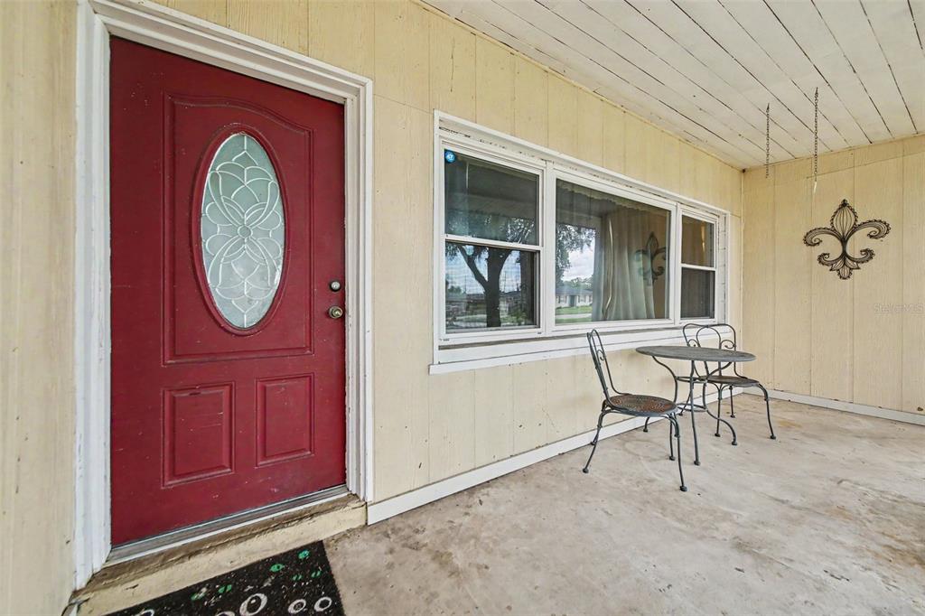 A red front door with a glass oval insert sits beside a windowed porch area — 1909 JASPER DRIVE, ORLANDO, FL