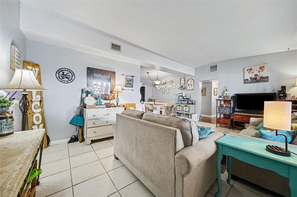A living room features light-colored tile floors, a beige sofa, and a teal side table — 1909 JASPER DRIVE, ORLANDO, FL