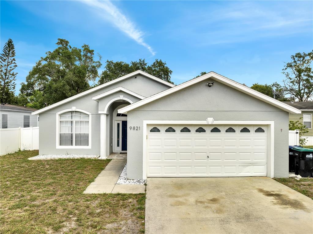 A single-story gray house with a white garage door and a front entrance — 9821 8TH AVENUE, ORLANDO, FL