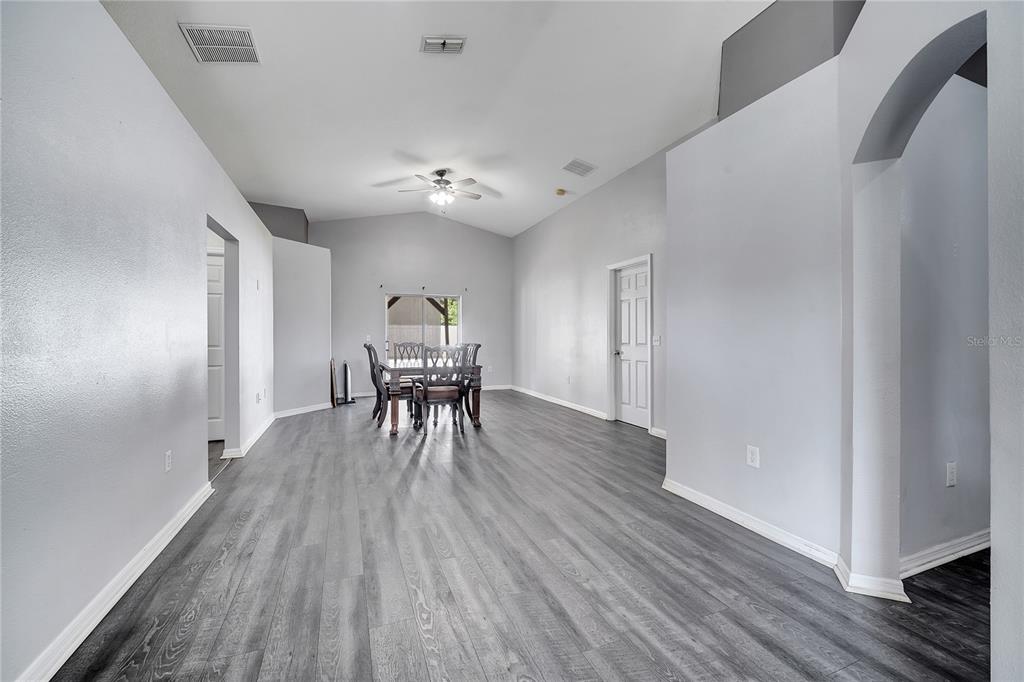 A dining area with gray wood-look flooring, vaulted ceilings, and a sliding glass door — 9821 8TH AVENUE, ORLANDO, FL