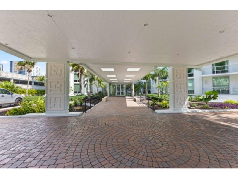 A paved circular driveway leads to a covered entrance with decorative pillars at a building — 1111 N GULFSTREAM AVENUE UNIT 5B, SARASOTA, FL