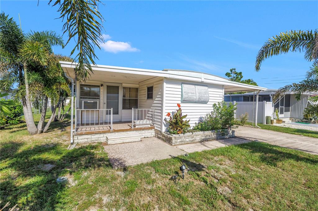 A white mobile home with a front porch, palm trees, and a concrete driveway — 2439 SANTIAGO DRIVE, HOLIDAY, FL