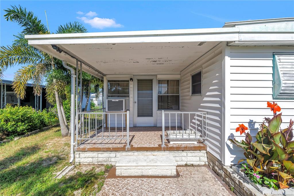A covered concrete porch with metal railings sits in front of a white mobile home — 2439 SANTIAGO DRIVE, HOLIDAY, FL