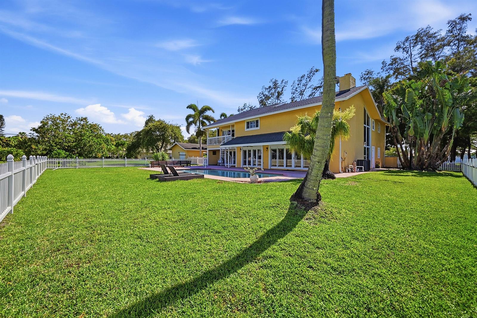 A wooden staircase with a railing overlooks a large window with views of palm trees — 10400 W Tara Boulevard, Boynton Beach FL 33437, BOYNTON BEACH, FL