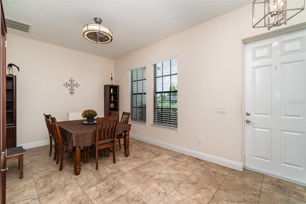 A dining room with tile flooring, a wooden table, and a white front door — 3137 SE 8TH AVENUE, CAPE CORAL, FL