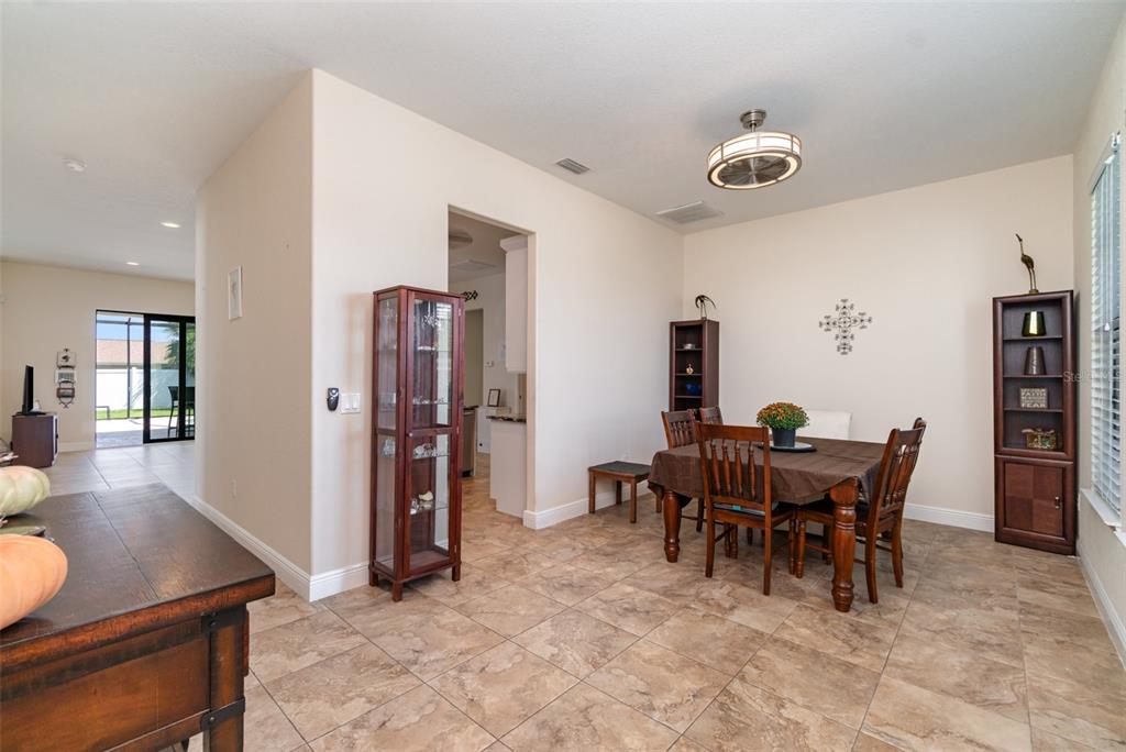 A dining room with tile floors, a wooden table, and a glass display cabinet — 3137 SE 8TH AVENUE, CAPE CORAL, FL