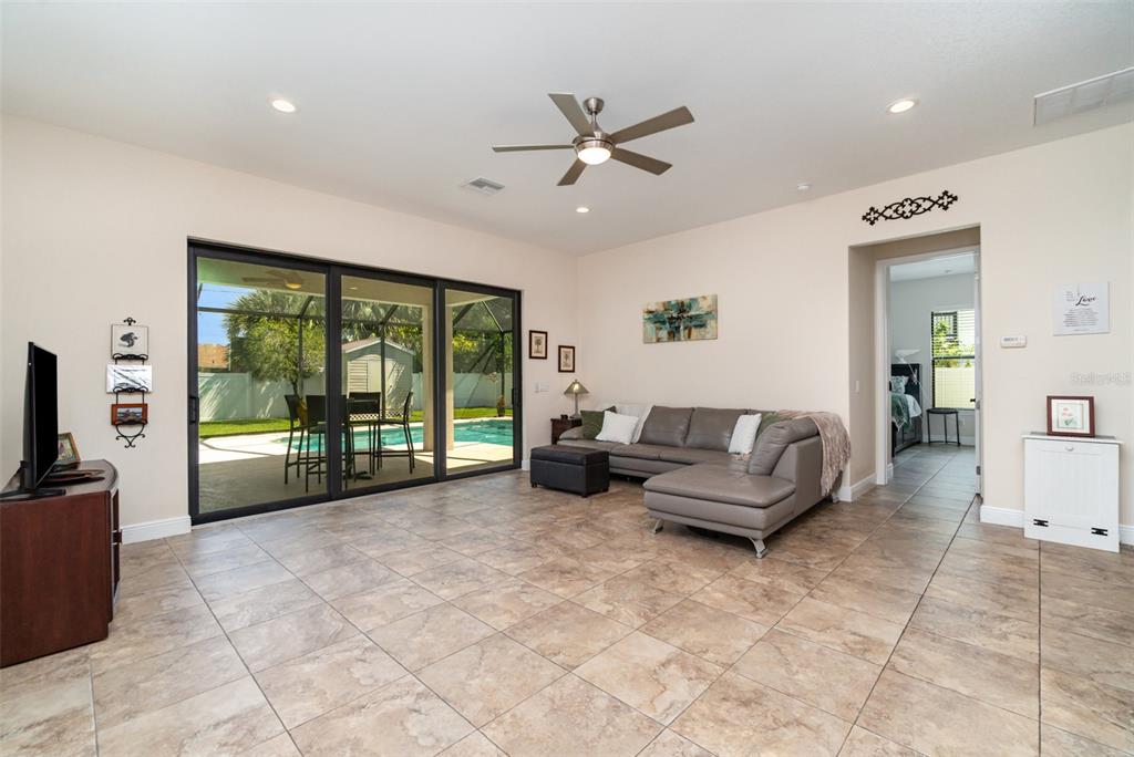 A living room features tile flooring, a gray sectional sofa, and sliding doors to a pool — 3137 SE 8TH AVENUE, CAPE CORAL, FL