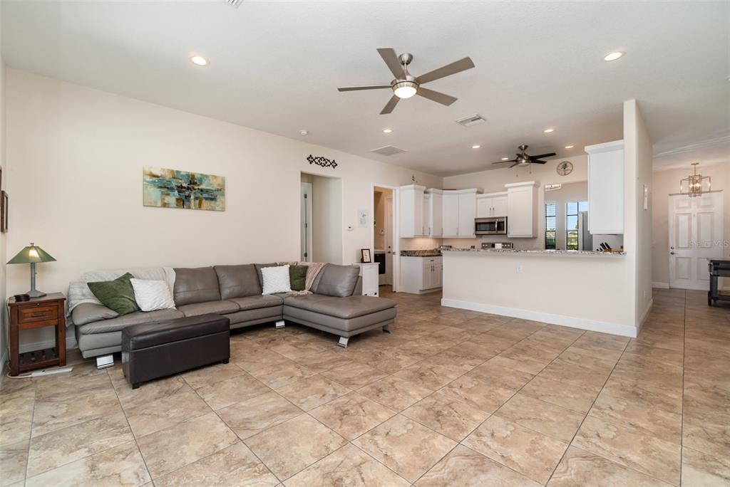 A living room with tile flooring, a gray sectional sofa, and an open kitchen — 3137 SE 8TH AVENUE, CAPE CORAL, FL