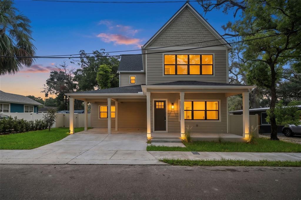 A two-story house with a front porch, attached carport, and light-colored siding at dusk — 5203 N 9TH STREET, TAMPA, FL