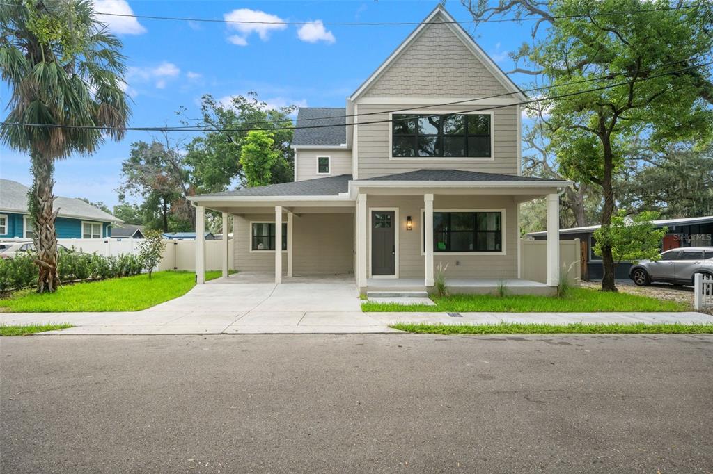 A two-story house with light gray siding, a front porch, and an attached carport — 5203 N 9TH STREET, TAMPA, FL