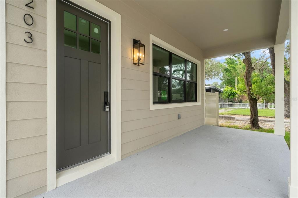 A covered front porch features a dark gray door, light siding, and a black lantern light — 5203 N 9TH STREET, TAMPA, FL