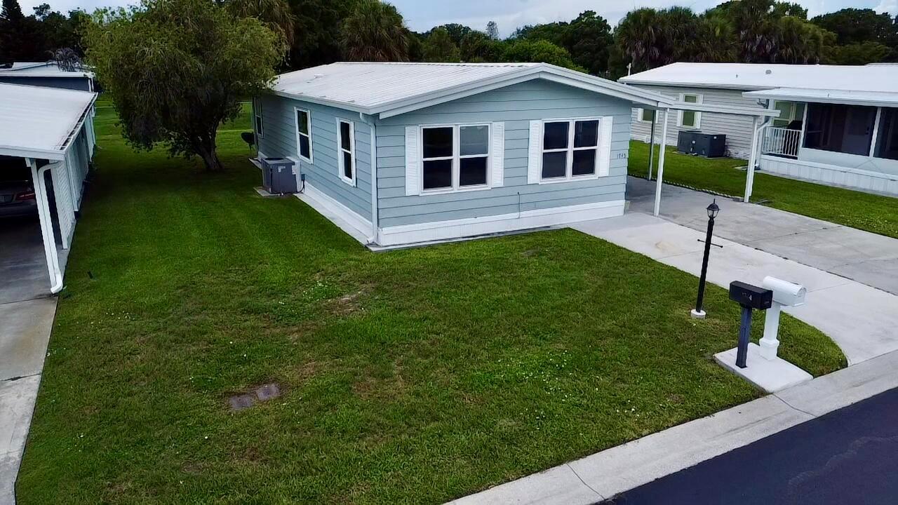 An aerial view of a light blue mobile home with a white roof and carport — 1745 SW 35th Circle, Okeechobee FL 34974, OKEECHOBEE, FL