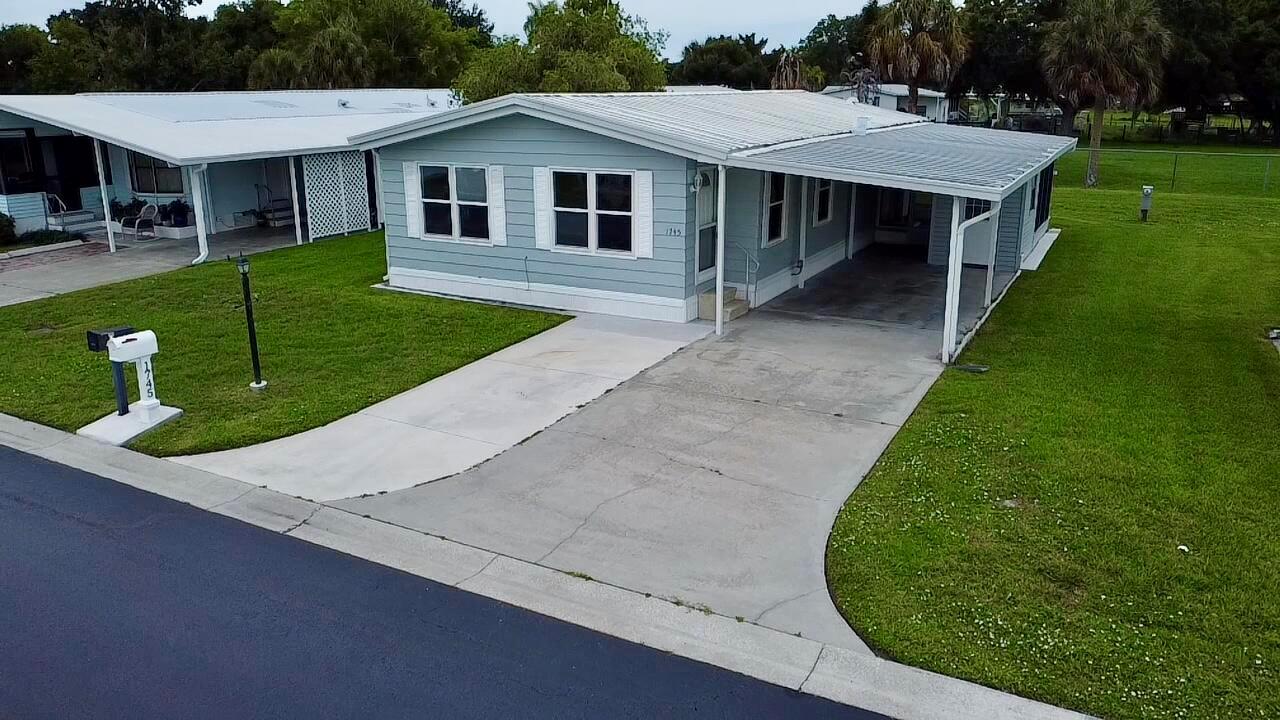 An aerial view of a light blue manufactured home with a concrete driveway and carport — 1745 SW 35th Circle, Okeechobee FL 34974, OKEECHOBEE, FL