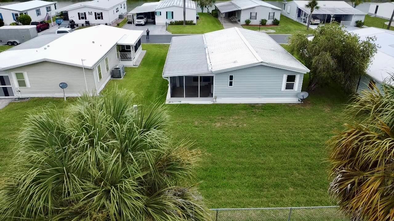 An aerial view shows a light blue manufactured home with a metal roof and yard — 1745 SW 35th Circle, Okeechobee FL 34974, OKEECHOBEE, FL