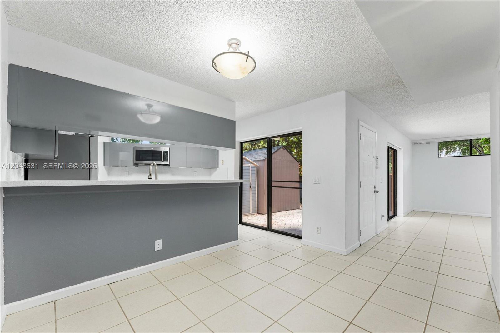 A kitchen with a gray breakfast bar opens to a dining area with tile floors — 8111 Severn Dr # D, Boca Raton FL 33433, BOCA RATON, FL