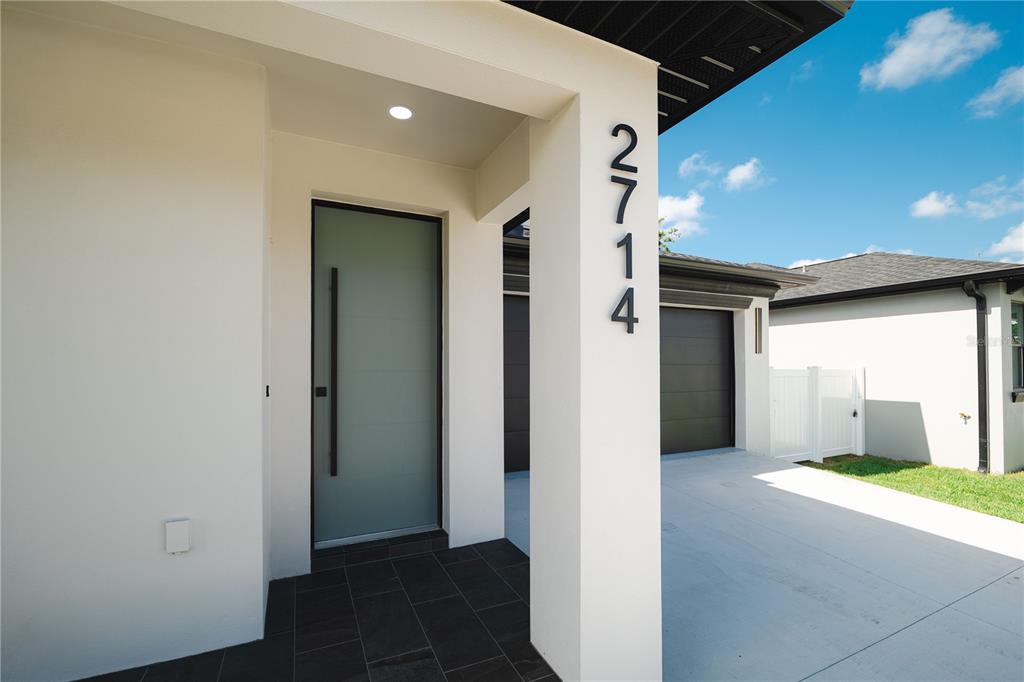 The exterior entrance of a modern home features a frosted glass door and house numbers — 2714 W TAMPA BAY BOULEVARD, TAMPA, FL