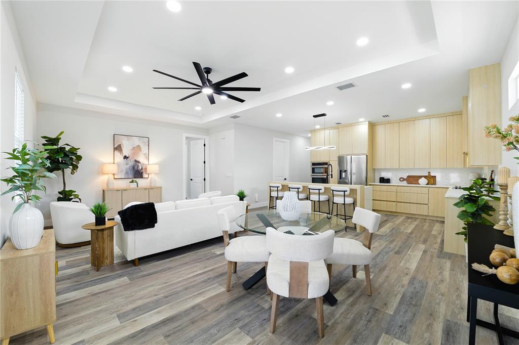 An open-concept living and dining area features light wood cabinetry, white furniture, and wood-look flooring — 2714 W TAMPA BAY BOULEVARD, TAMPA, FL