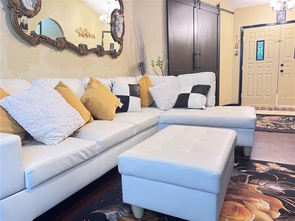 A white sectional sofa with a matching ottoman sits in a living room with a mirror — 12555 BROOKSIDE STREET, SPRING HILL, FL