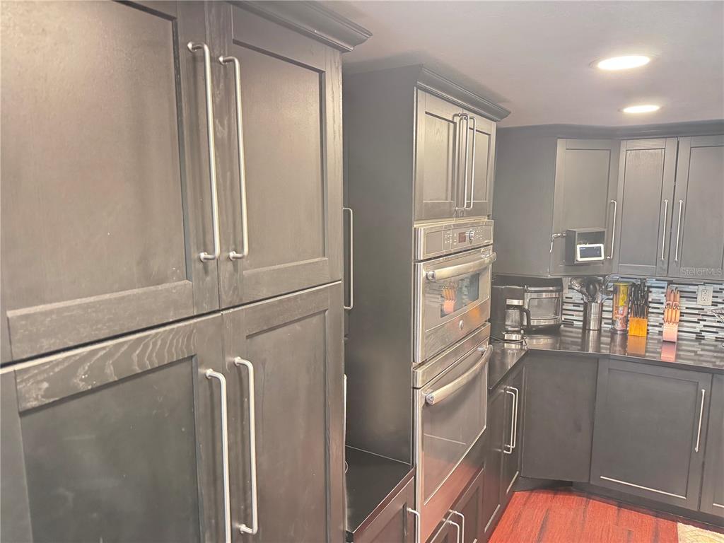 A kitchen features dark wood cabinets, stainless steel appliances, and a built-in double oven — 12555 BROOKSIDE STREET, SPRING HILL, FL