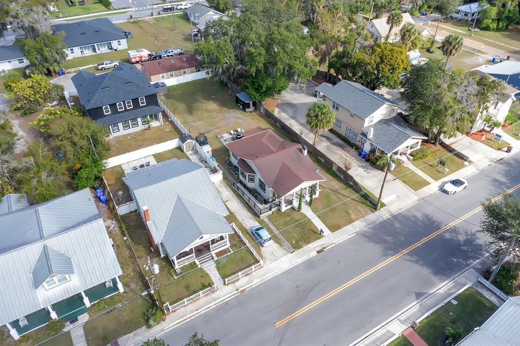 An aerial view shows several houses with metal and shingle roofs along a paved street — 721 MABBETTE STREET, KISSIMMEE, FL
