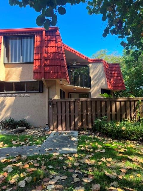 A two-story townhouse with a red tile roof, a balcony, and a wooden privacy fence — 8129 Severn Dr # C, Boca Raton FL 33433, BOCA RATON, FL