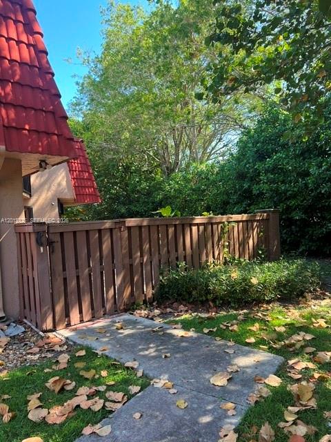 A wooden fence encloses a patio area next to a building with a red roof — 8129 Severn Dr # C, Boca Raton FL 33433, BOCA RATON, FL
