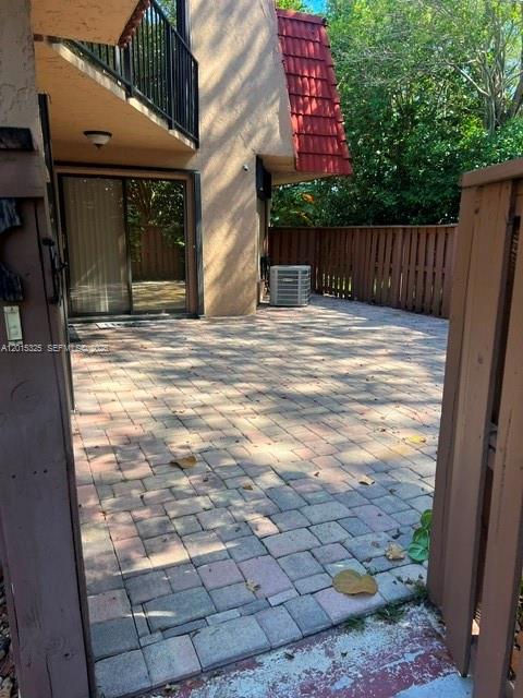 A paved patio area sits outside a building with a sliding glass door and balcony — 8129 Severn Dr # C, Boca Raton FL 33433, BOCA RATON, FL
