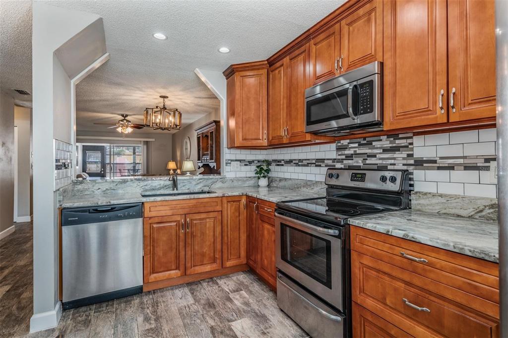 A kitchen with wood cabinets, stainless steel appliances, and granite countertops — 11308 VERSAILLES LANE UNIT C, PORT RICHEY, FL