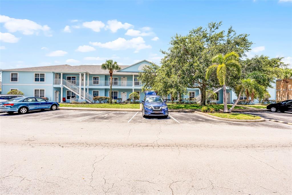 A two-story light blue apartment building sits behind a parking lot with several cars — 3111 SUN LAKE COURT UNIT B, KISSIMMEE, FL