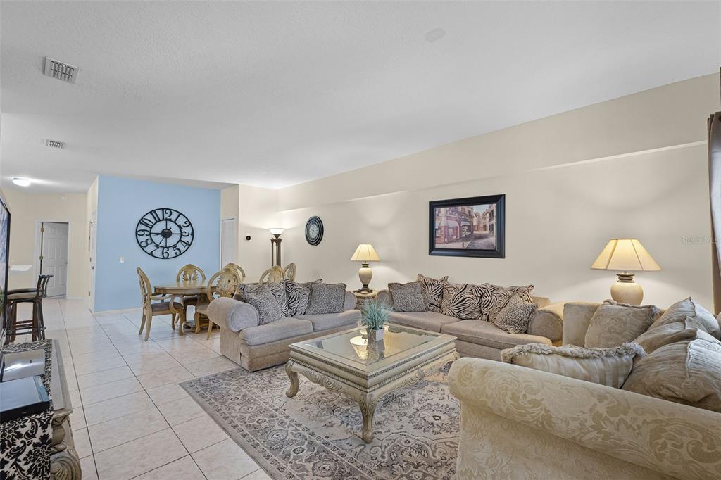 A living room with tile flooring, a large area rug, and a dining area beyond — 3111 SUN LAKE COURT UNIT B, KISSIMMEE, FL
