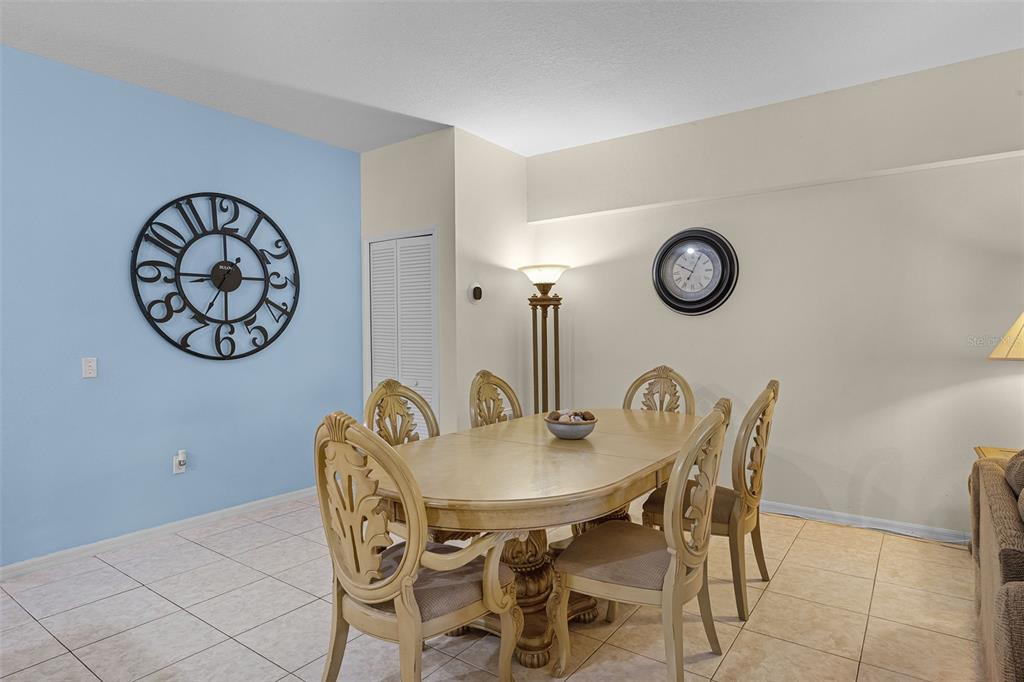 A dining room features a light wood table with six chairs, tiled floors, and two clocks — 3111 SUN LAKE COURT UNIT B, KISSIMMEE, FL