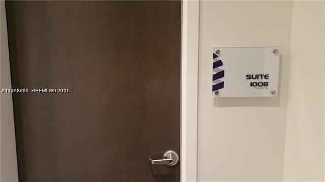 A dark wood door with a silver handle next to a Suite 1008 sign — 20200 W Dixie Hwy # 1008, Miami FL 33180, MIAMI, FL