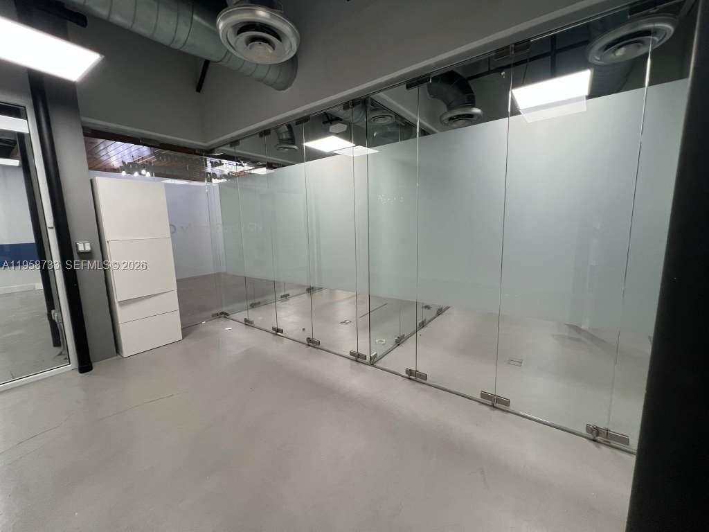 An office space features glass partition walls, a white storage cabinet, and exposed ceiling ductwork — 20200 W Dixie Hwy # 1008, Miami FL 33180, MIAMI, FL
