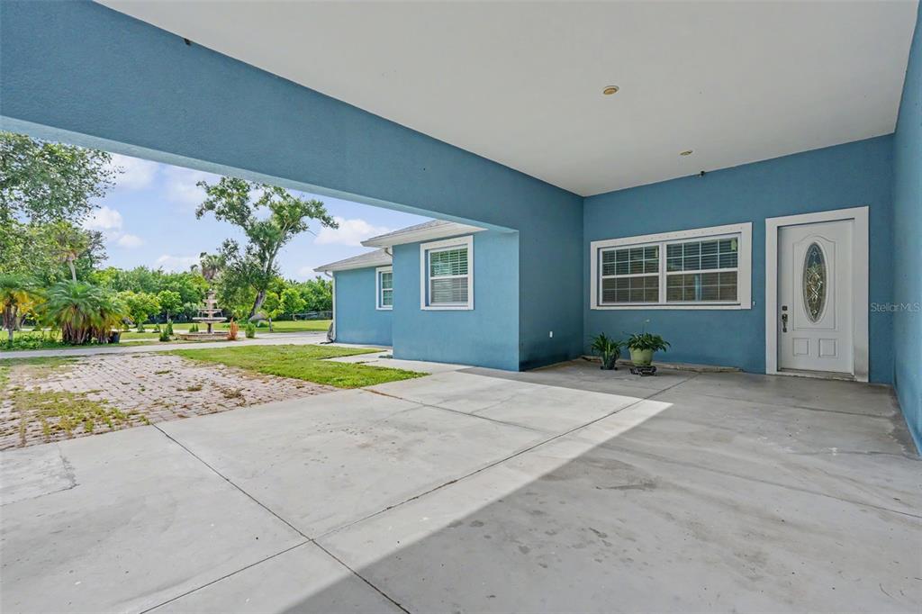 A covered concrete patio leads to a white front door on a blue exterior wall — 2007 61ST STREET, SARASOTA, FL