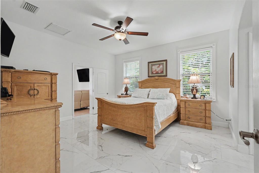 A spacious living room features white marble-look tile flooring, tan leather furniture, and arched doorways — 2007 61ST STREET, SARASOTA, FL